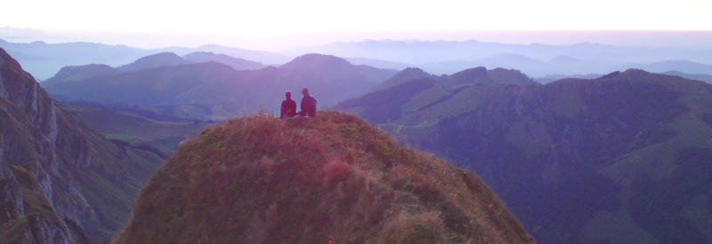 Ein Paar bei Sonnenuntergang auf einem Berg mit Blick auf die Alpenwelt